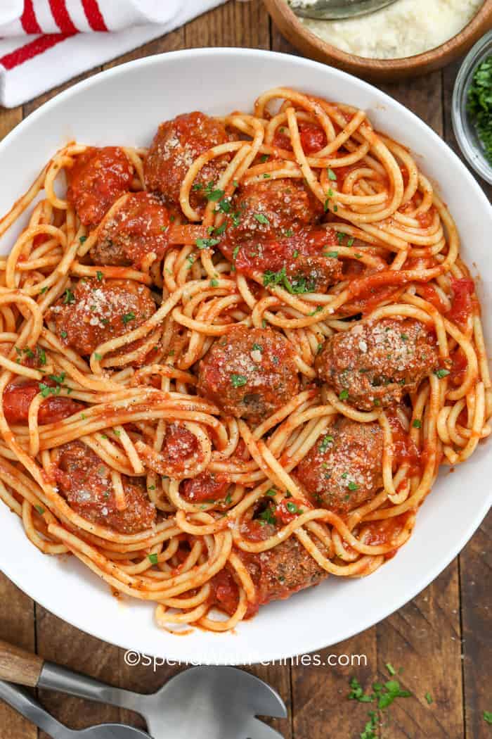 A plate of spaghetti and meatballs topped with parsley and parmesan cheese