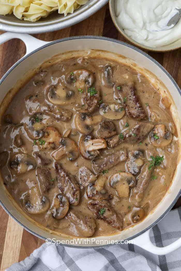Make this easy beef stroganoff for a classic and comforting meal. Tender cuts of sirloin steak are cooked in a gravy made from a little flour, sour cream, beef broth, mushrooms, butter, and more. This is the best spooned over egg noodles or potatoes. So easy, so creamy, and oh so good! #easybeefstroganoff #beefstroganoff #beefstroganoffrecipe #spendwithpennies Overhead shot of Beef Stroganoff in a pot