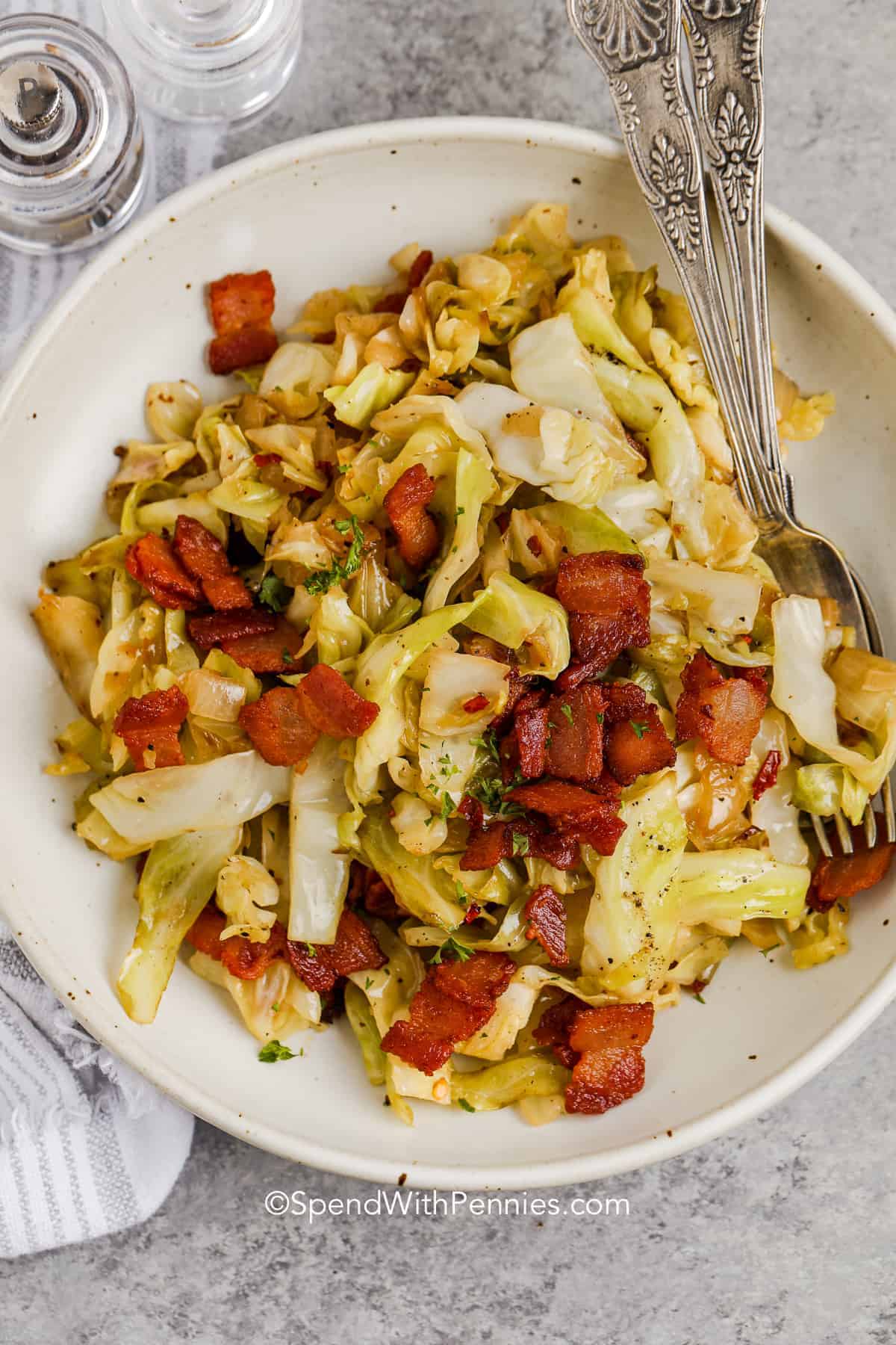 Fried Cabbage is a quick and easy southern side dish that can easily be made into a main dish. Made keto-style with bacon and onion, it's savory and delish. Stir in some chili flakes for extra spice or mix things up with meat like chicken, sausage, or beef. Red quinoa, rice, or pork with Chinese noodles make this dish into something completely different. #friedcabbage #withbaconandonion #recipeseasy #spendwithpennies a plate of fried cabbage