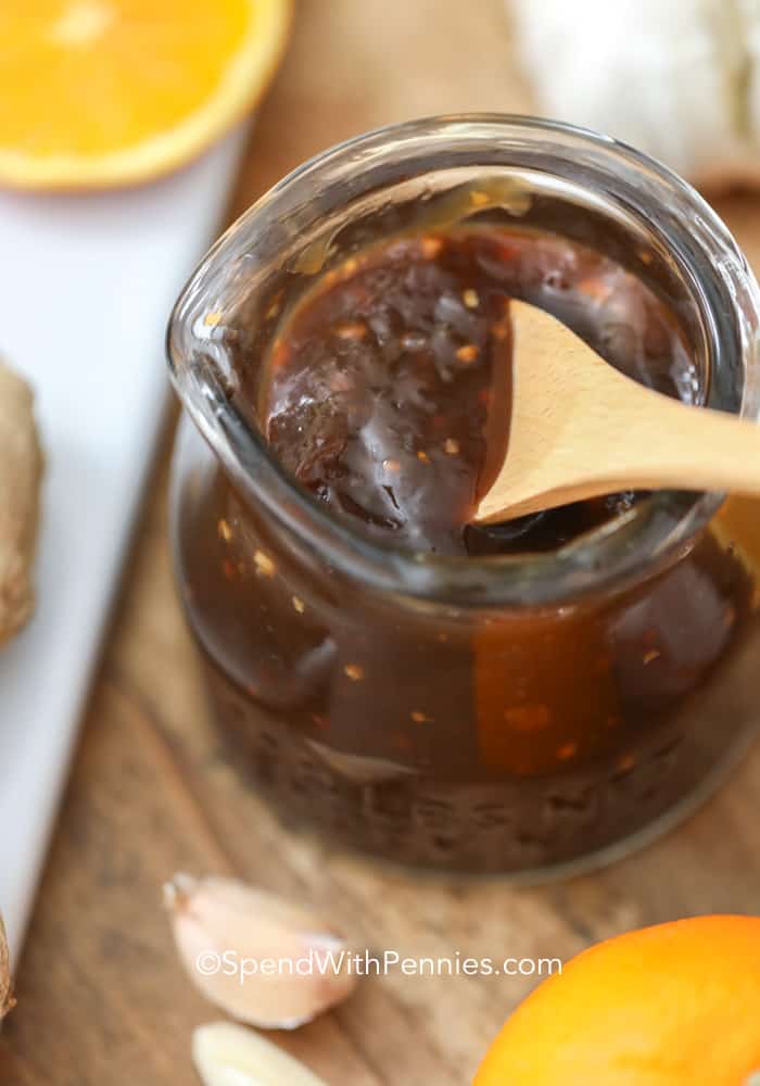 Creating your own Teriyaki sauce at home is definitely worth it! With simple ingredients like soy sauce, ginger, and garlic, you have everything you need. This homemade sauce brings an explosion of incredible flavor to your favorite dishes, whether it's chicken, beef, or veggies. It's a fun and satisfying way to take your meals to a whole new level of deliciousness. Give it a try and prepare for a mouthwatering experience! #teriyakisauce #homemade #teriyaki #asian #spendwithpennies Wooden spoon in a glass jar of teriyaki sauce