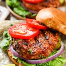 cooked turkey burger on a hamburger bun with tomatoes on top