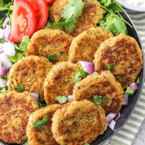 Heard falafels on a plate with tomatoes red onion and cilantro