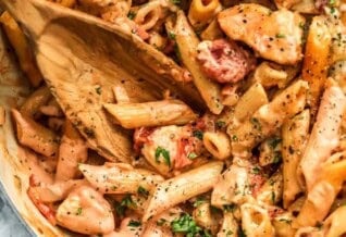 a pot of pasta in a creamy tomato sauce with chicken