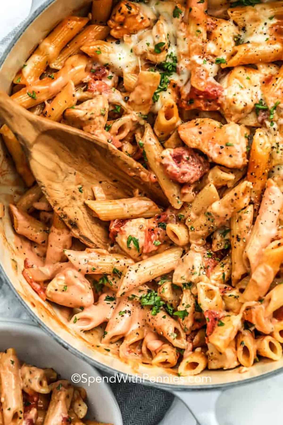 a pot of pasta in a creamy tomato sauce with chicken