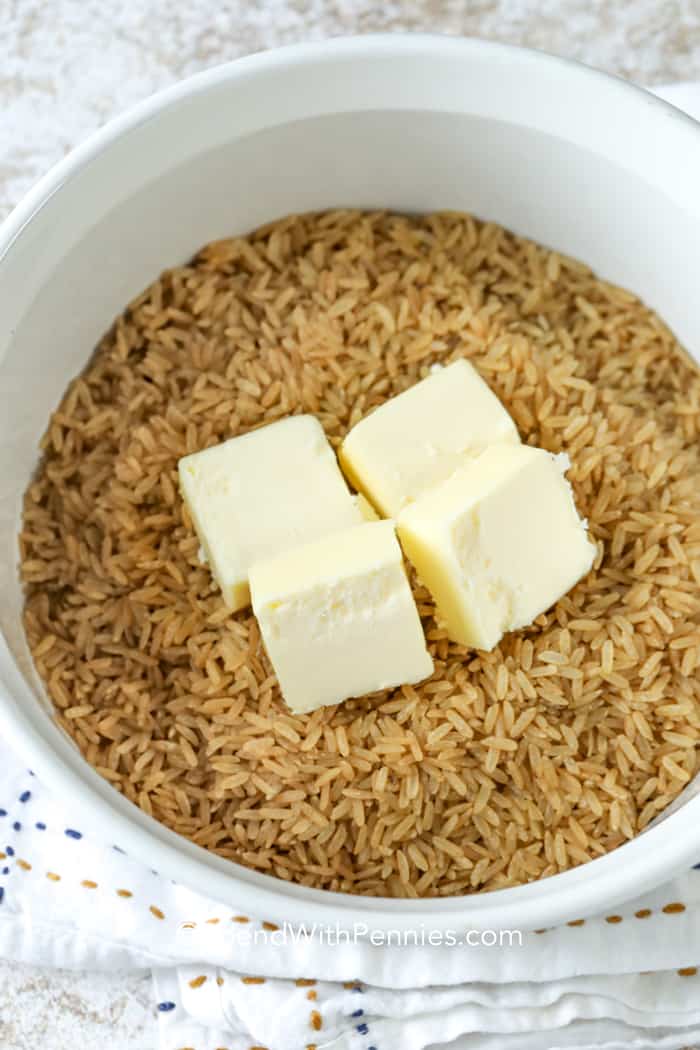 Oven Brown Rice in a white bowl with four pads of butter on top