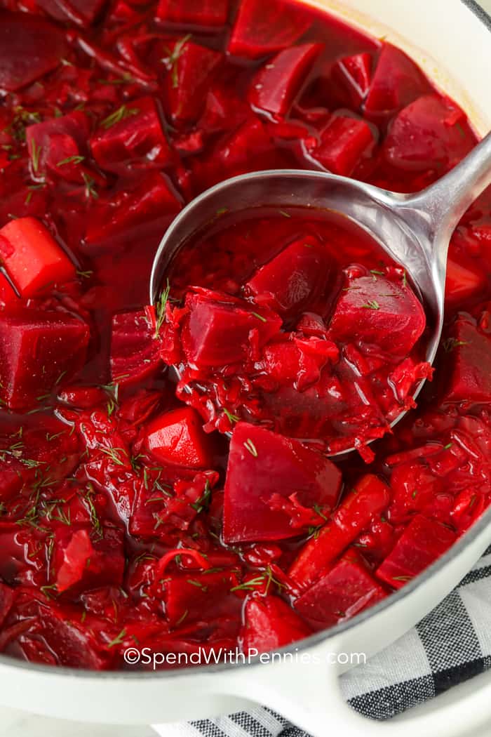There is nothing quite like a traditional borscht recipe! This soup is made with ingredients like cabbage and beets and is garnished with sour cream and dill! It is such an easy and delicious soup you will want to make lots. Bonus, it tastes even better the next day! #borscht #soup #homemade #beetsoup #spendwithpennies scooping a ladle of Hot Borscht