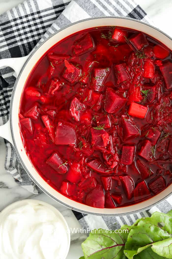 Borscht is a traditional beet soup made with cabbage, sour cream, and dill! It is the perfect combination of earthy sweetness with a little bit of sour. This easy soup recipe tastes even better the next day so be sure to make lots! #borscht #soup #homemade #beetsoup #spendwithpennies a pot of Hot Borscht