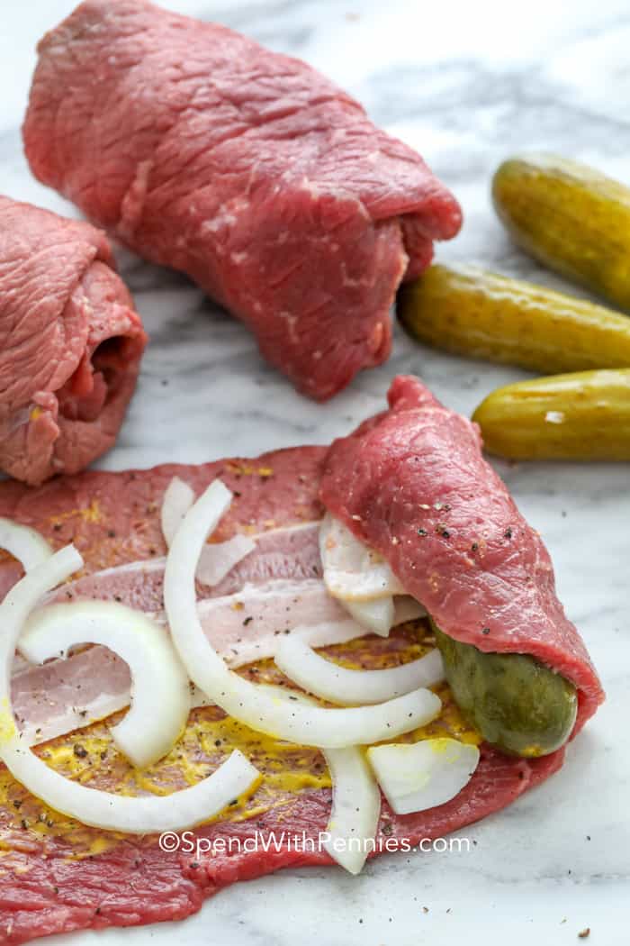 Jautienos ruladenas suteikia tradicinį vokišką komfortą su garstyčių, šoninės, svogūnų ir krapų raugintų agurkų sluoksniais, apvyniotais minkšta jautiena ir apskrudinta prieš troškinant. Iš lėto virimo gaunamas gilus, pikantiškas padažas, puikiai tinkantis patiekti ant bulvių ar makaronų. Šiame recepte suderinti sotūs skoniai, žinomi ingredientai ir paprasta technika, todėl jis yra mėgstamiausias bet kokiai progai. #išleisti su centais Jautienos ruladenas vyniojamas ant marmurinės lentos