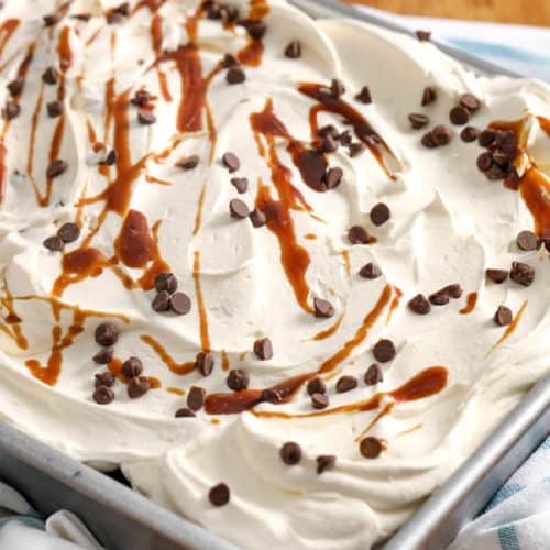 Better Than Sex cake in a sheet pan with whipped cream caramel sauce and chocolate chips on top