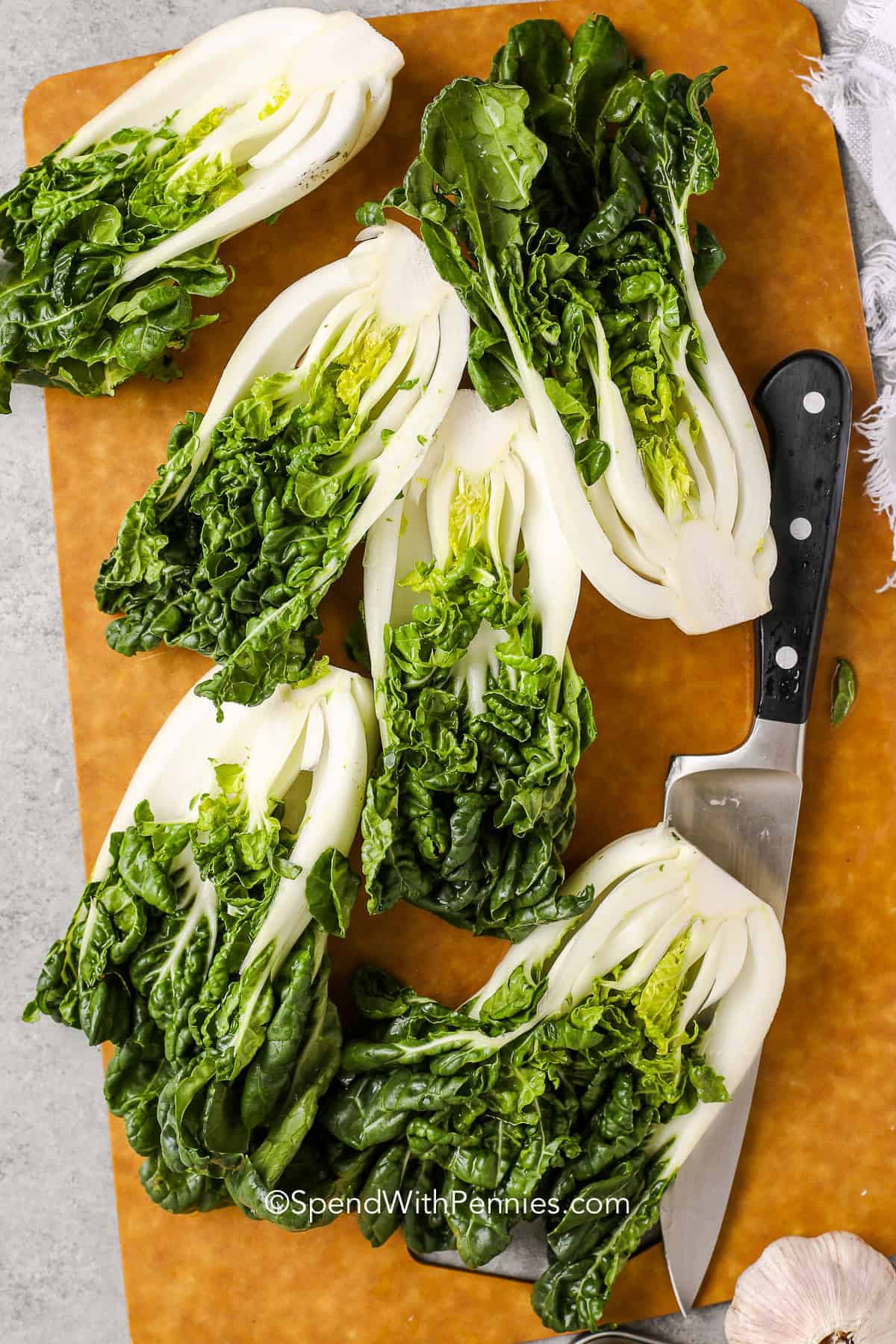 bok choy cut in half on a cutting board with a knife 