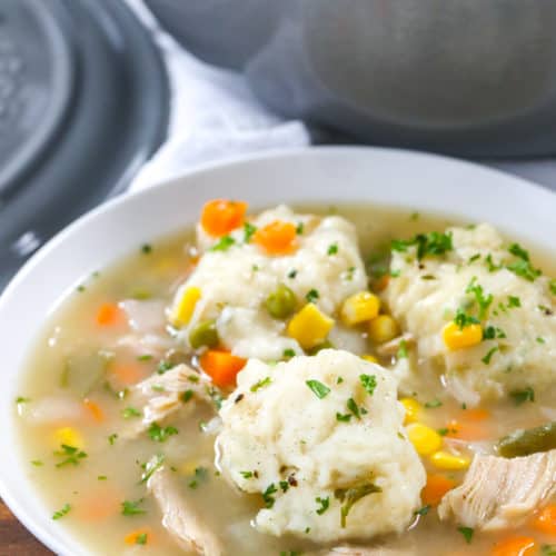 Turkey soup and dumplings in a white bowl with parsley on top