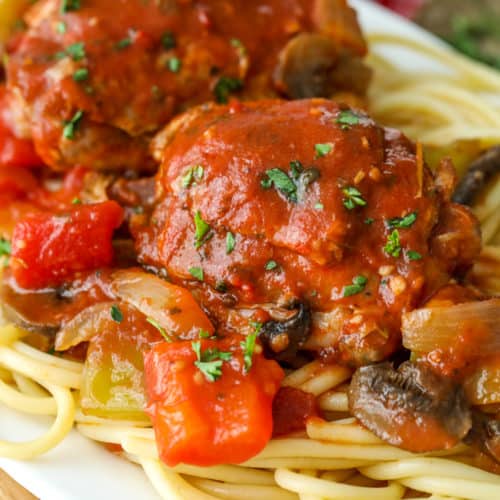 Slow cooker chicken cacciatore on a plate with noodles and parsley