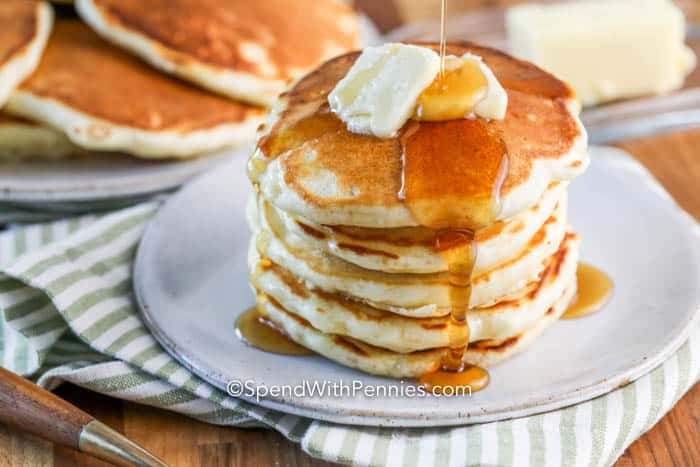 Homemade pancakes are a delicious treat made right in your own kitchen. Fluffy and golden-brown, they can be topped with syrup, fresh fruit, or even a dollop of whipped cream for a delightful breakfast or snack. Pancakes can even be made for dinner with a side of bacon and eggs! #pancakes #fluffypancakes #homemade #spendwithpennies Stack of pancakes on a plate with butter and syrup