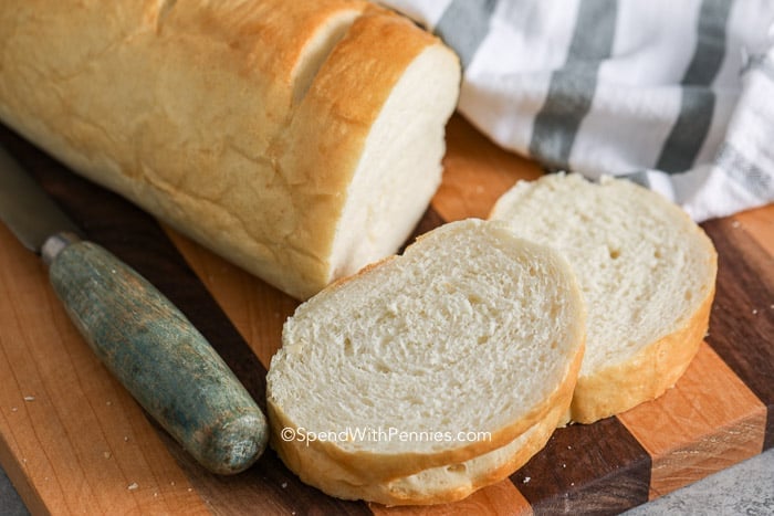 Slices of French bread on a wooden board with a knife