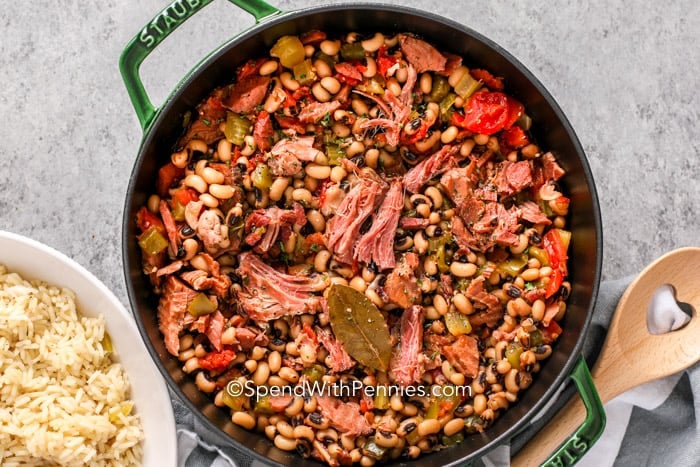 Hoppin John in a pot with a wooden spoon and a bowl of rice