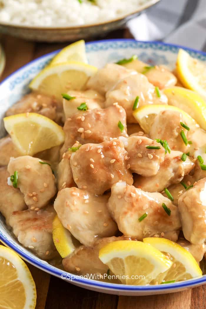 Lemon chicken lemon chicken in a bowl with sesame seeds chives and lemons