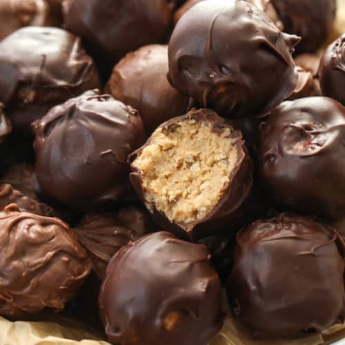 Peanut butter balls in a bowl with a bite taken out of 1