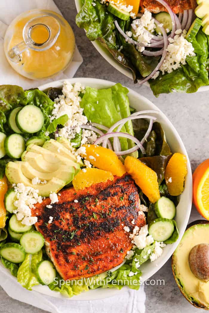 huge bowl of Blackened Salmon Salad with dressing and ingredients beside
