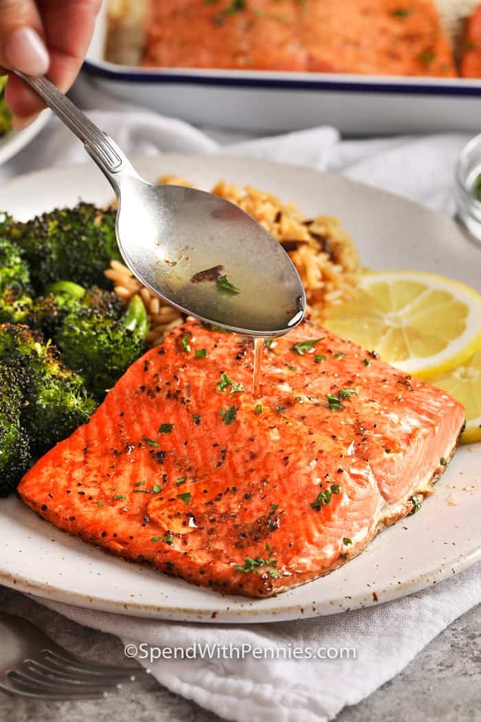 A broiled salmon served with broccoli and rice, being drizzled with leftover marinade. 