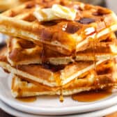 a plate of homemade waffles with syrup and butter