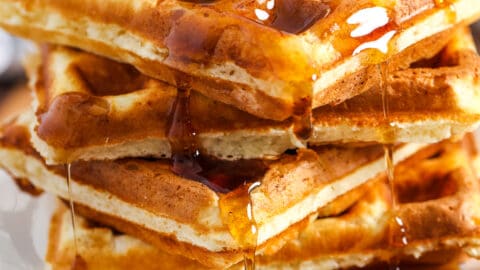 a plate of homemade waffles with syrup and butter