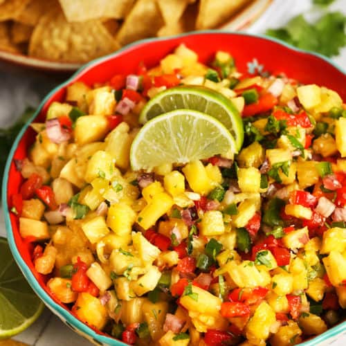 Pineapple salsa topped with lime wedges and cilantro