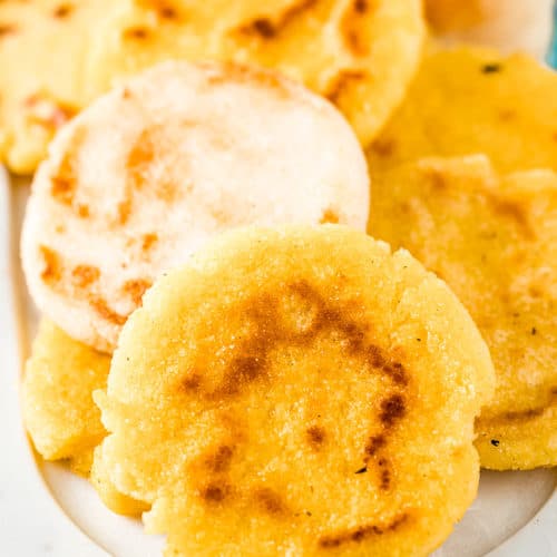 Yellow and white arepas on a serving dish.