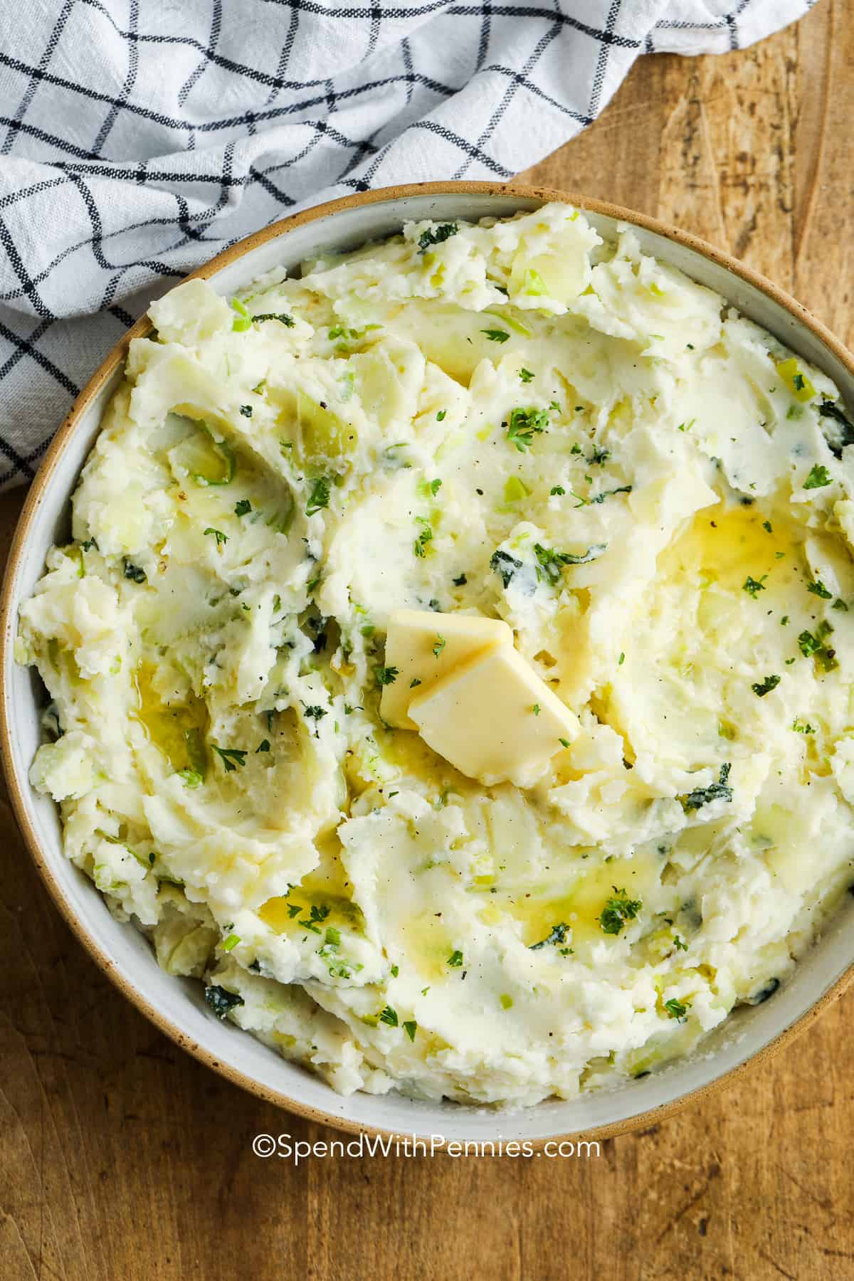 Colcannon is a traditional Irish dish consisting of cabbage and onion (or leeks) fried until tender and gently folded into rich and creamy mashed potatoes. It is the perfect dish for St. Patrick's Day (or any other day you're craving the best ever comfort food)! #colcannon #mashedpotatoes #cabbage #cabbageandbacon #spendwithpennies colcannon with pats of butter shown overhead