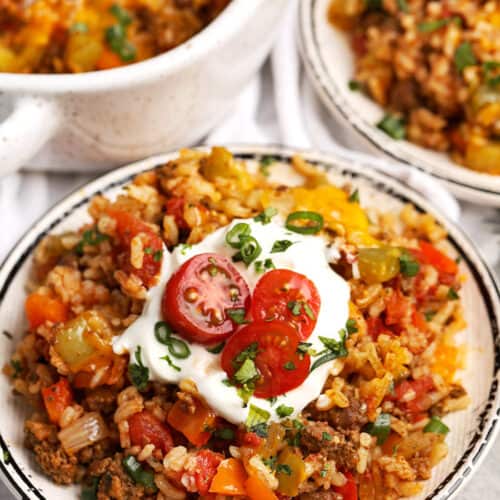 Taco Stuffed Pepper Casserole in a dish with tomatoes and sour cream on top