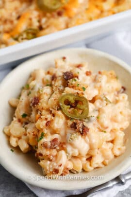 jalapeno mac and cheese on a white plate and casserole dish behind
