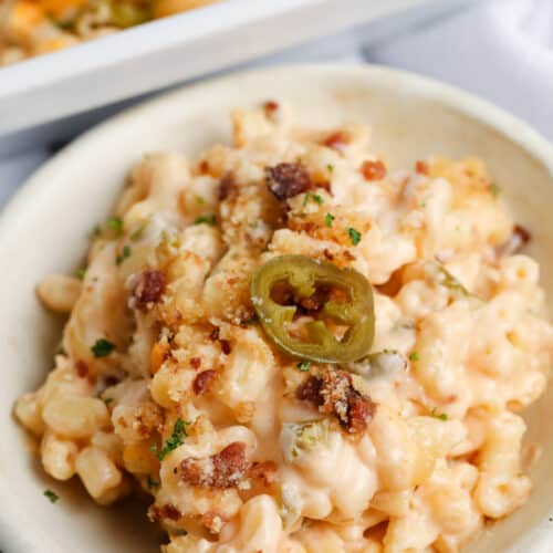 jalapeno mac and cheese on a white plate and casserole dish behind