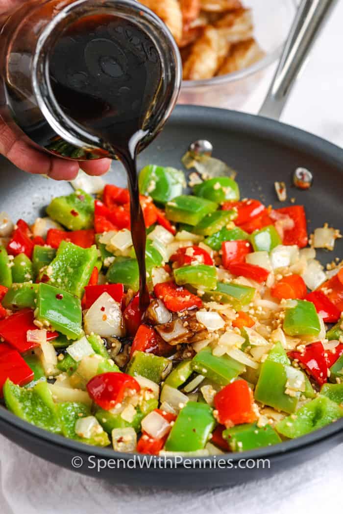 vegetables for kung pao shrimp in a frying pan with sauce being poured over top