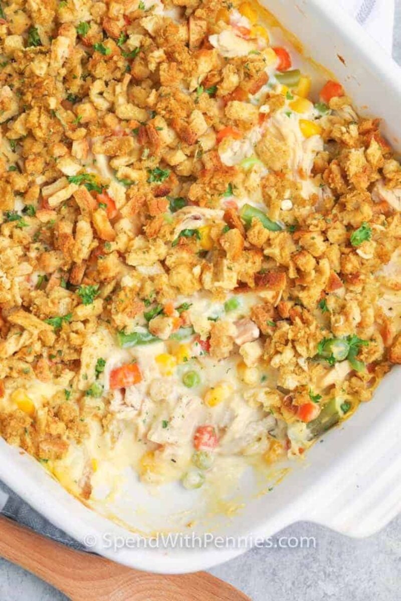 This Chicken Stuffing Casserole is a great weekday option! Ready in about 30 minutes, this dish will be ready and on the table in no time! #spendwithpennies #chickenstuffingcasserole #recipe #stovetopstuffing #casserole chicken stuffing casserole in a baking dish with a scoop taken out of it.