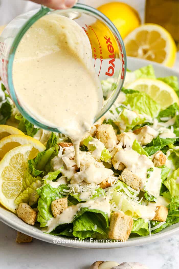 pouring dressing on caesar salad