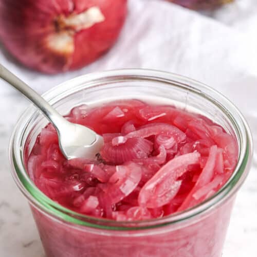 Pickled Red Onions in a jar with a fork in it
