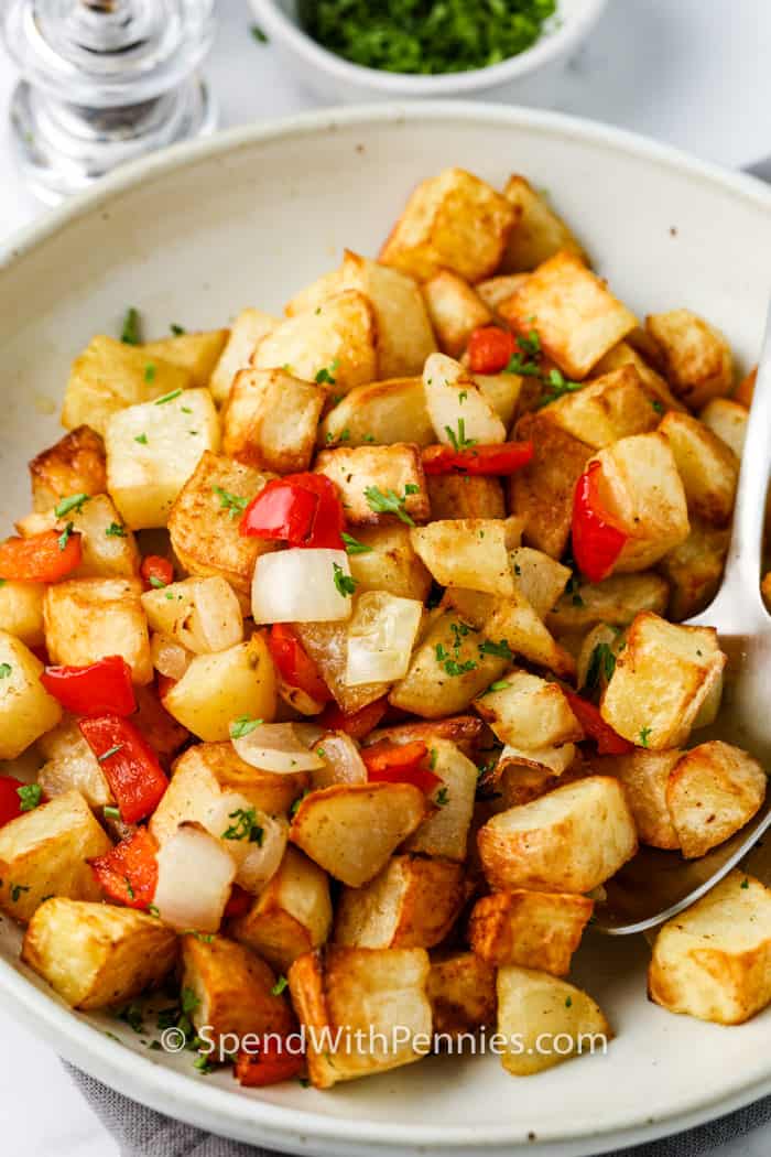 plated Air Fryer Home Fries with a spoon and garnish