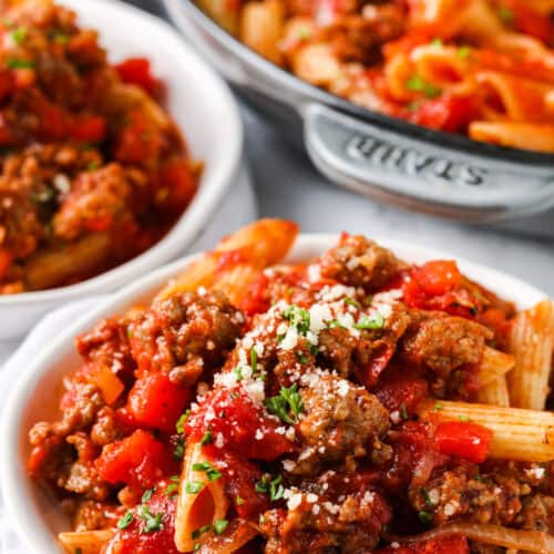 Sausage Pasta in a bowl with pan and bowl full in the background