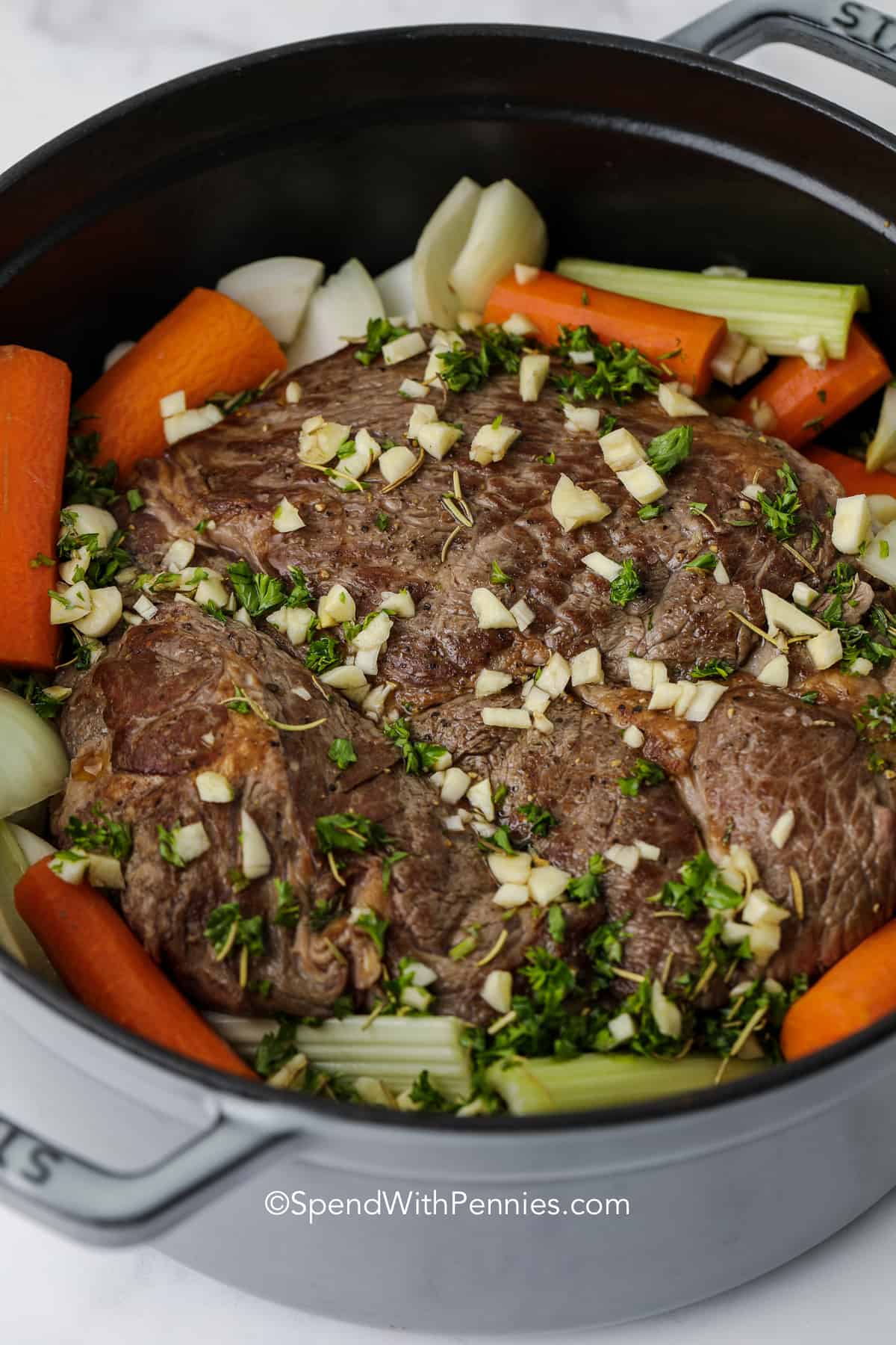 beef and veggies in a pot with garlic and seasonings to make pot roast recipe