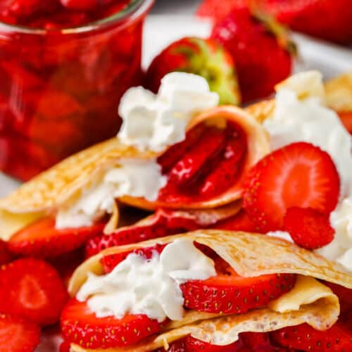 Strawberry Crepes on a plate with jar of strawberries in the background