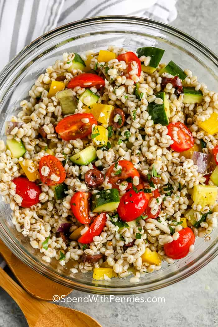 Barley Salad in a glass bowl with a wooden spoon on the side
