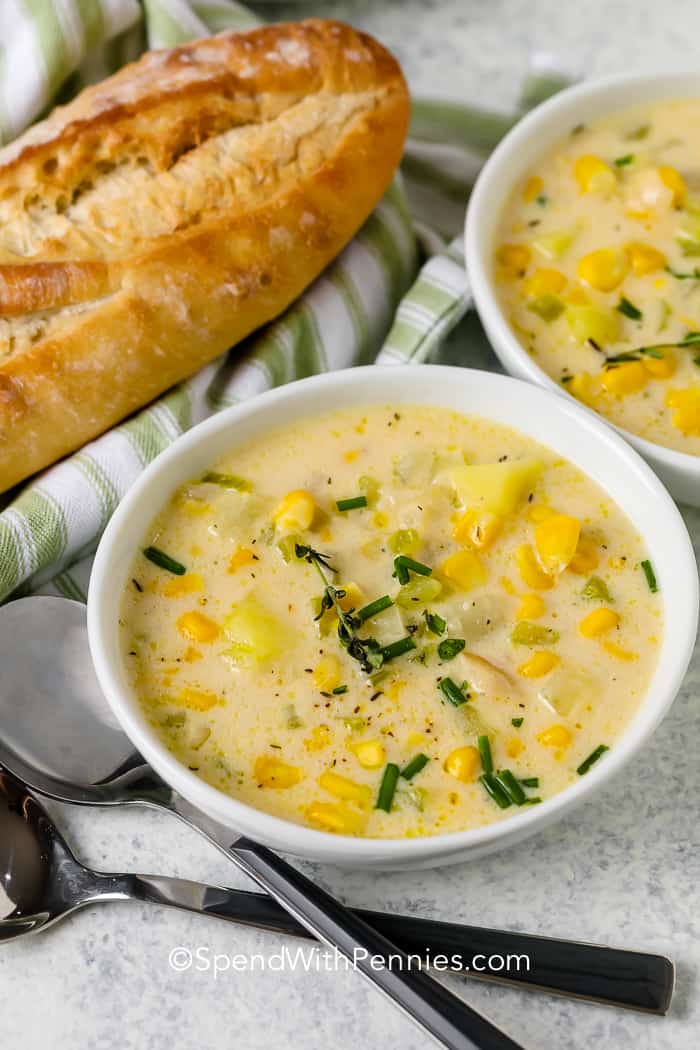 Corn soup served in a bowl with a bread on the side 