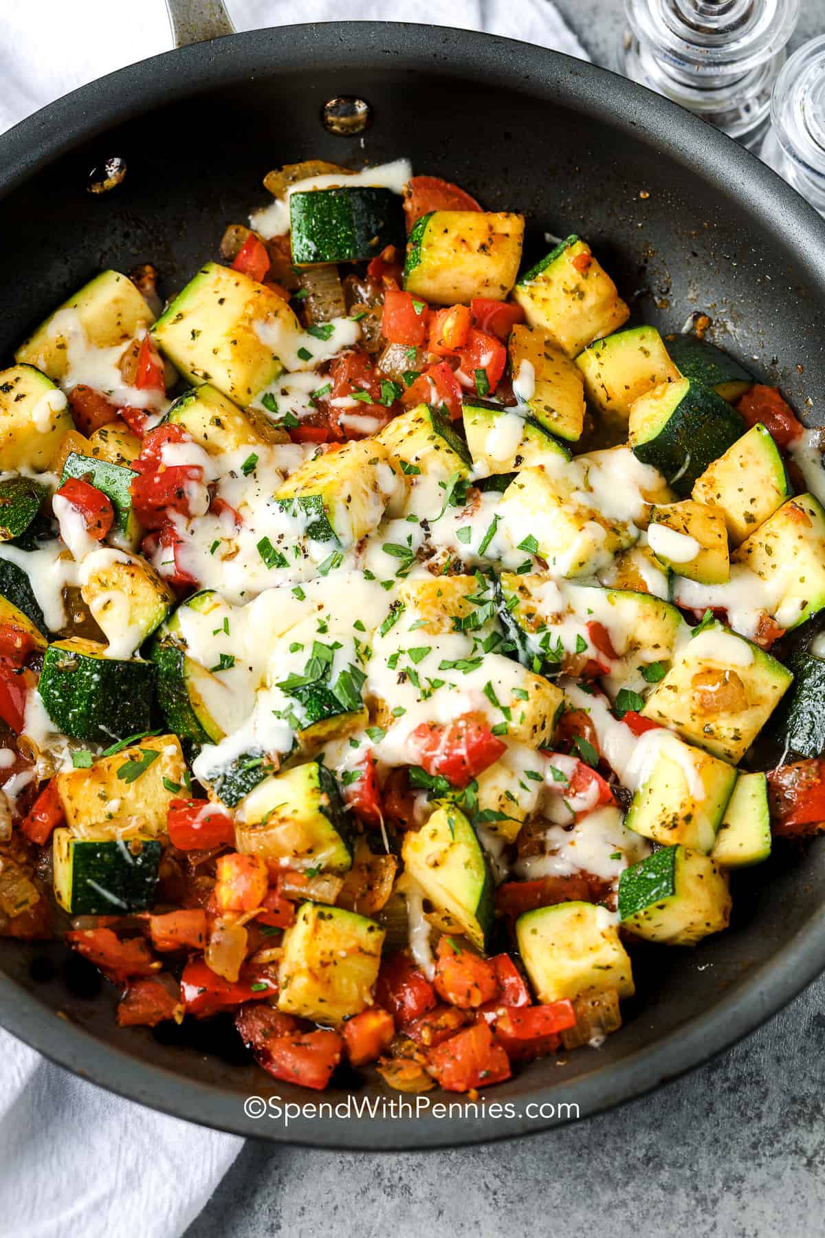 Sauteed zucchini and tomatoes in a pan with cheese