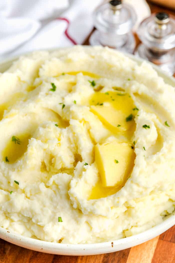 close up of Cream Cheese Mashed Potatoes with melted butter on top and salt and pepper shakers