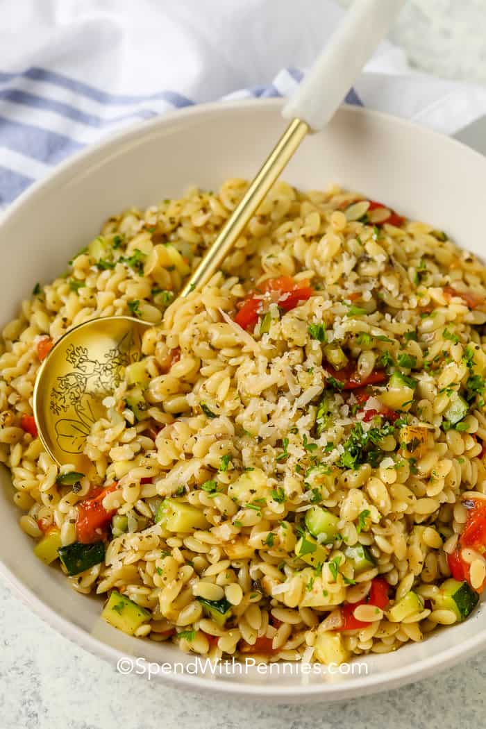 A bowl of zucchini orzo with a serving spoon