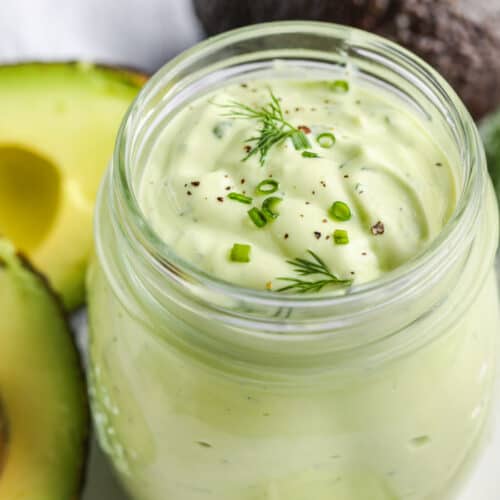 Avocado Ranch Dressing in a jar with avocados in the background