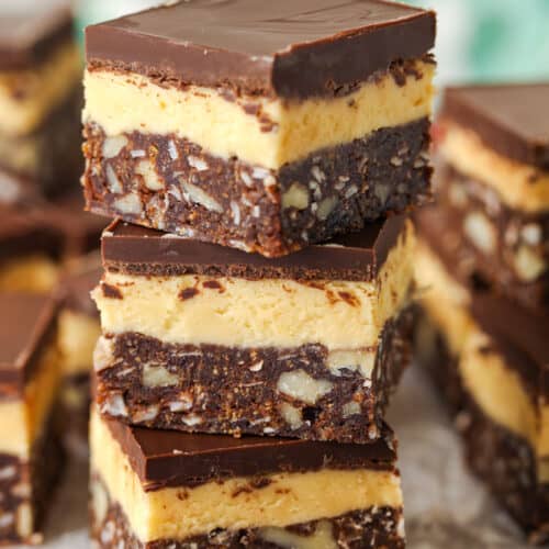 three Nanaimo Bars stacked with Nanaimo Bars in the back