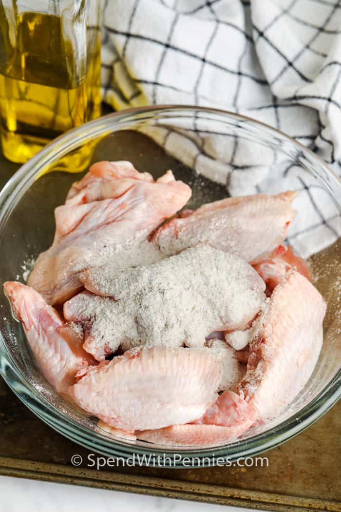 These baked chicken wings turn out crispy using basic pantry items and a few helpful steps. Patting the wings dry and baking them on a rack lets hot air move all around. A short chill without a cover helps the coating stick. One easy add-in helps the skin puff as it cooks. Bake until golden, then broil briefly for color. Toss with any sauce you like. Reheat leftovers on a rack to bring the crunch back. #spendwithpennies ingredients to make Actually Crispy Oven Baked Wings in a glass bowl