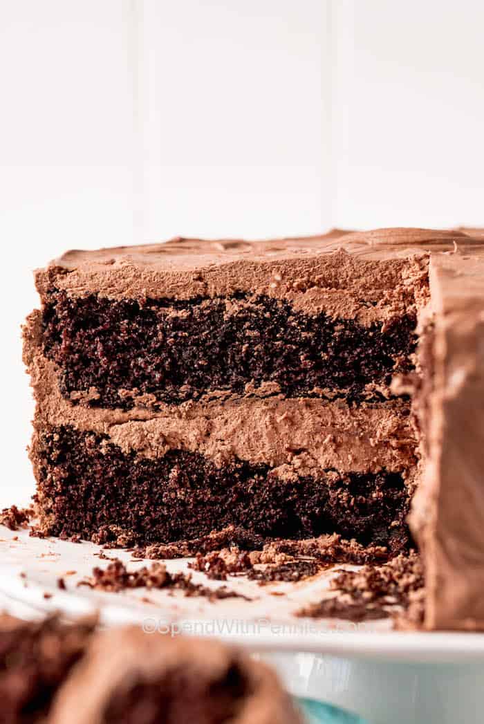 This chocolate cake is decadent, moist, and rich which will be so hard to resist. What's more, is that this homemade cake recipe is so easy to make and is the best way to finish off an evening meal. Frost it with some luscious buttercream chocolate or vanilla frosting for a dessert that they will all rave over. #chocolatecake #chocolatecakerecipe #cake #spendwithpennies cut chocolate cake on a plate