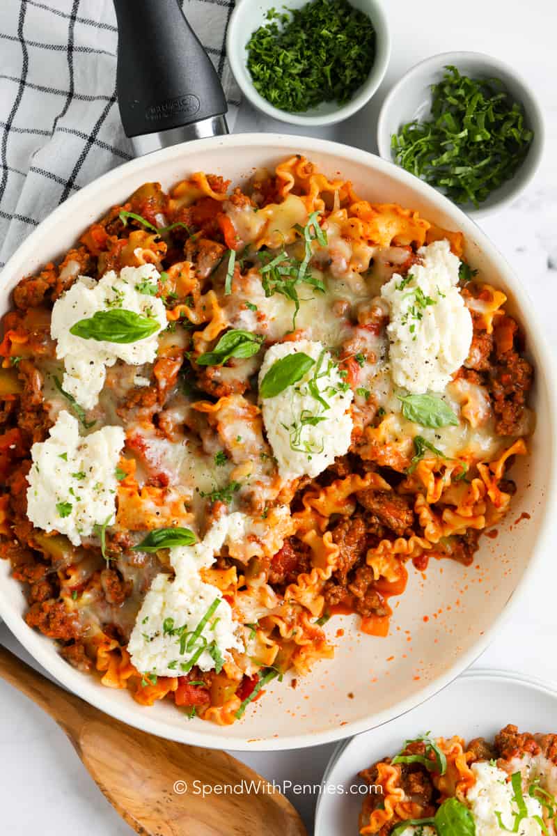 lasagna skillet in a pan topped with cheese and basil