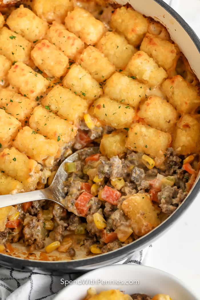 serving spoon scooping classic tater tot casserole